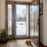ProVia Deluxe storm door viewed from inside a Cleveland home during winter, showing snow outside and boots by the entryway.