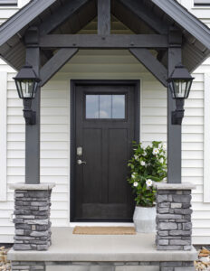 ProVia front entry door in Rustic Bronze finish framed by stone columns and white siding on a Northeast Ohio home exterior