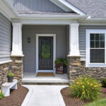 ProVia front entry door in a deep painted finish with decorative glass insert, complementing gray siding and stone exterior on a Northeast Ohio home