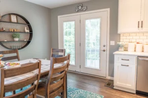 White hinged patio doors with built-in blinds opening from a dining area to an outdoor deck.